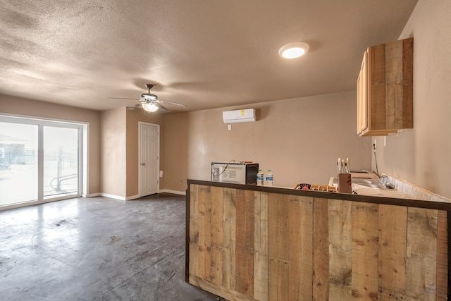 kitchen featuring concrete floors, baseboards, a wall mounted air conditioner, a peninsula, and a textured ceiling