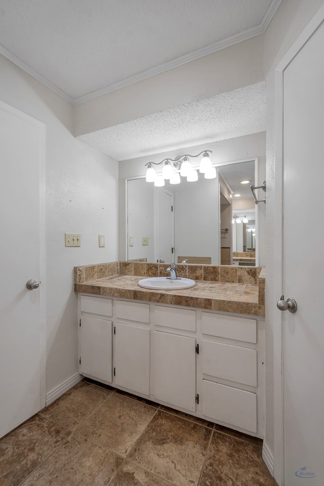 bathroom featuring vanity, a textured ceiling, baseboards, and ornamental molding