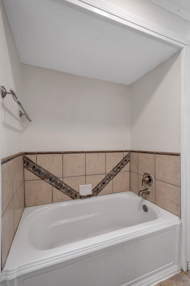 bathroom with a garden tub and a textured ceiling