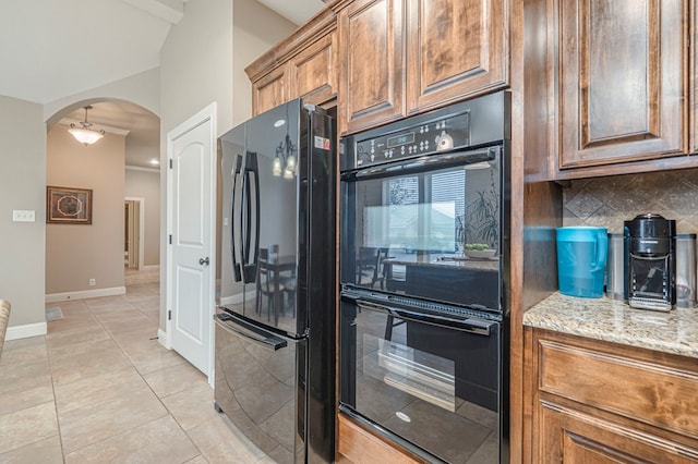 kitchen featuring light tile patterned flooring, light stone countertops, backsplash, and black appliances