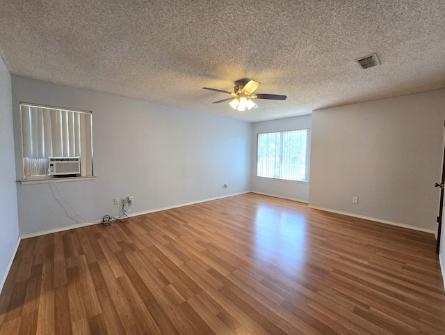 spare room featuring wood finished floors, ceiling fan, baseboards, a textured ceiling, and cooling unit