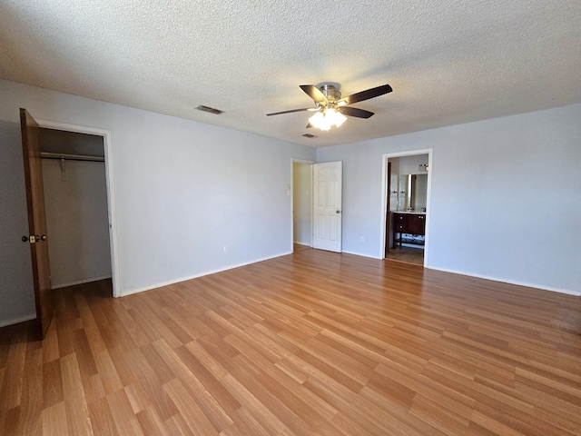 unfurnished bedroom featuring light wood-type flooring, a textured ceiling, ceiling fan, baseboards, and a closet