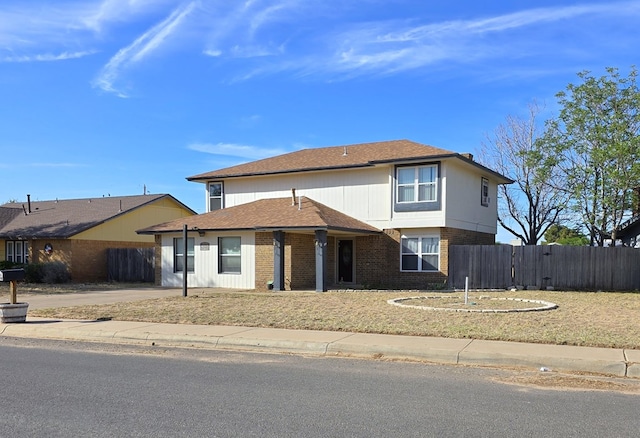 traditional-style home featuring fence, brick siding, and roof with shingles