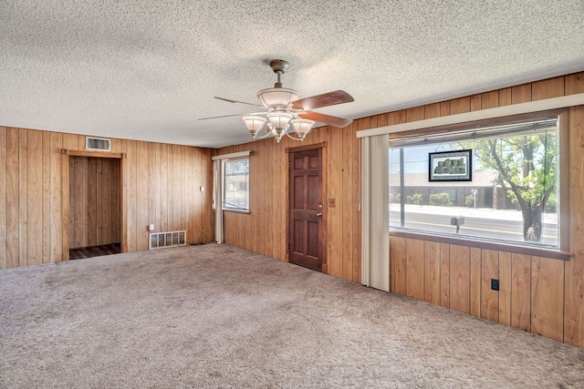 1707 Goliad St, Big Spring, TX 79720 - empty room with carpet flooring, wood walls, a ceiling fan, and a textured ceiling