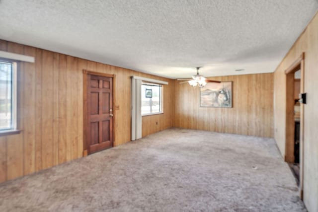 1707 Goliad St, Big Spring, TX 79720 - carpeted empty room featuring healthy amount of natural light, wood walls, and a textured ceiling