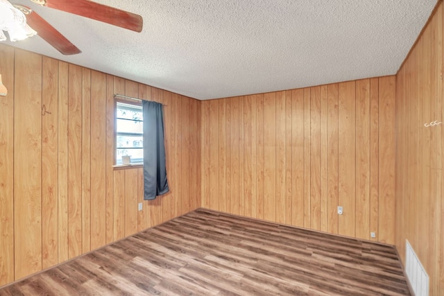 1707 Goliad St, Big Spring, TX 79720 - empty room with a textured ceiling, a ceiling fan, wood walls, and wood finished floors