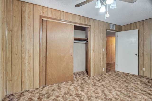 1707 Goliad St, Big Spring, TX 79720 - unfurnished bedroom with wood walls, carpet flooring, a closet, a textured ceiling, and a ceiling fan