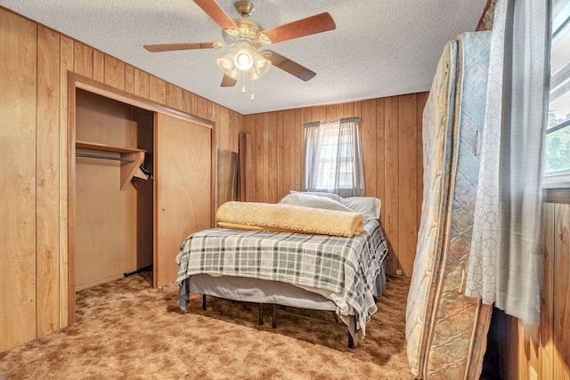 1707 Goliad St, Big Spring, TX 79720 - bedroom with wooden walls, carpet floors, a closet, a textured ceiling, and ceiling fan