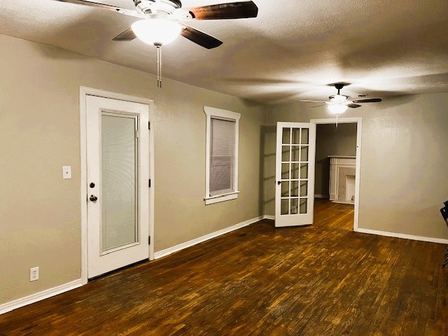 empty room with dark wood-style flooring, ceiling fan, a textured ceiling, and baseboards