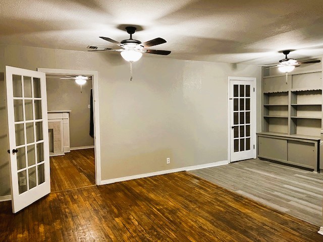 empty room with dark wood-style floors, ceiling fan, a textured ceiling, and baseboards