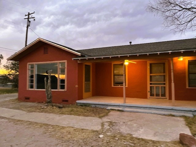 back of house featuring a shingled roof, crawl space, and stucco siding