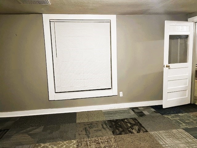 interior space featuring a textured ceiling, visible vents, and baseboards