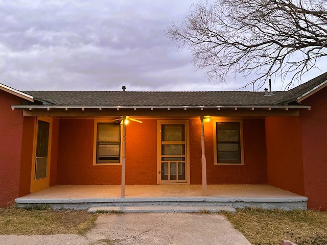 exterior space with a patio area, a shingled roof, and stucco siding