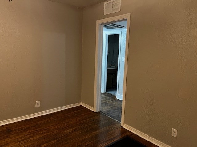 spare room featuring baseboards, visible vents, and dark wood-type flooring