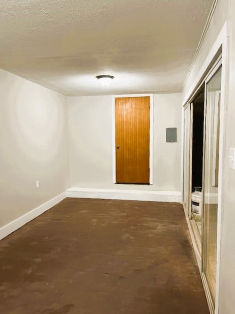 spare room featuring baseboards, concrete flooring, and a textured ceiling