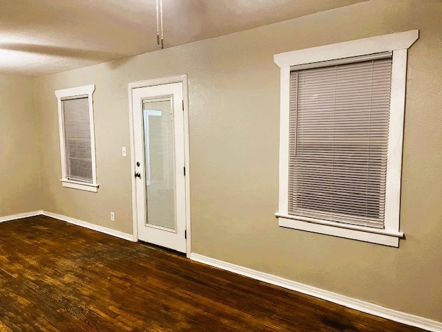 empty room with dark wood-type flooring and baseboards