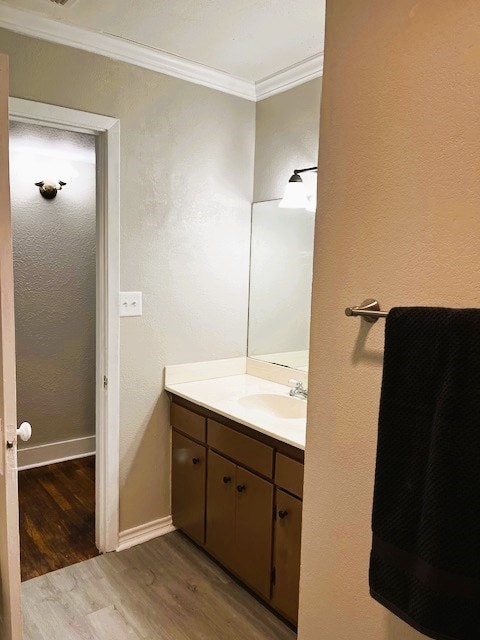 bathroom with crown molding, vanity, baseboards, and wood finished floors