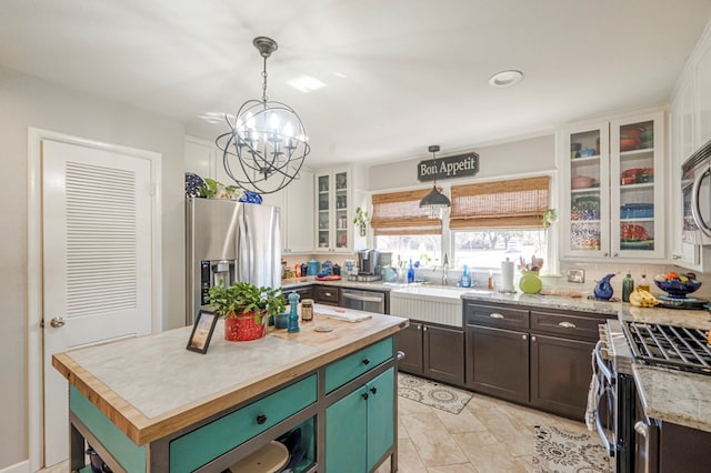 kitchen with hanging light fixtures, a notable chandelier, a sink, stainless steel appliances, and butcher block counters