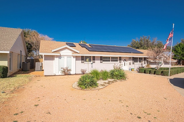 rear view of property with solar panels, a gate, brick siding, cooling unit, and a shingled roof