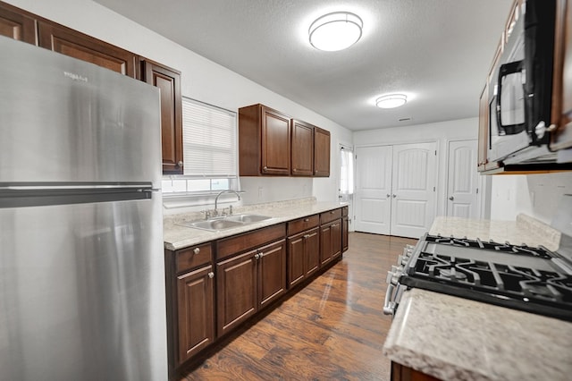 kitchen with dark hardwood / wood-style floors, sink, dark brown cabinetry, stainless steel appliances, and a textured ceiling