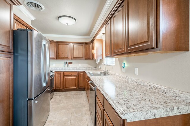 1829 Petroleum Dr, Odessa, TX 79762 - kitchen with appliances with stainless steel finishes, a sink, crown molding, brown cabinetry, and light countertops
