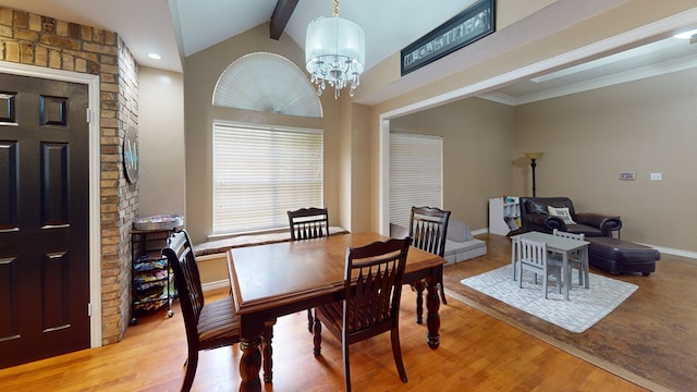dining space featuring vaulted ceiling with beams, baseboards, an inviting chandelier, and wood finished floors