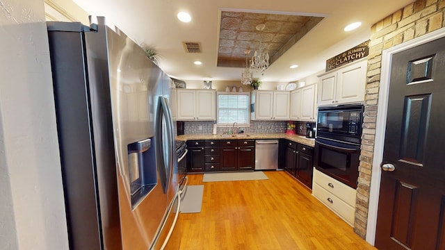 kitchen with visible vents, tasteful backsplash, a sink, light wood-style flooring, and black appliances