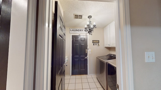 clothes washing area featuring visible vents, washer and clothes dryer, a chandelier, cabinet space, and light tile patterned floors