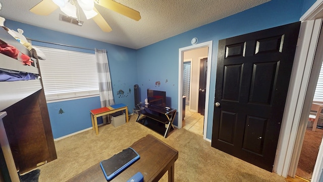 carpeted bedroom featuring visible vents, a ceiling fan, and a textured ceiling