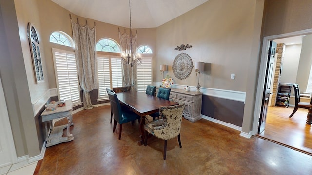dining space with an inviting chandelier, concrete floors, baseboards, and high vaulted ceiling