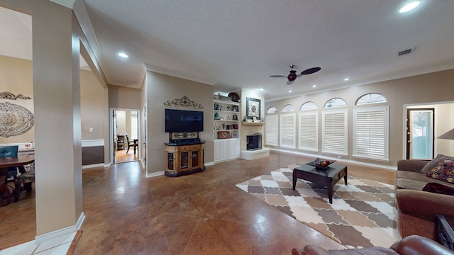 living area featuring crown molding, visible vents, recessed lighting, a fireplace with raised hearth, and a ceiling fan