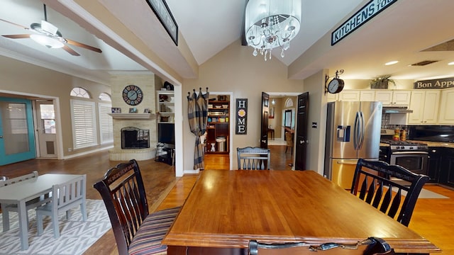 dining room featuring visible vents, light wood finished floors, ceiling fan with notable chandelier, and a fireplace