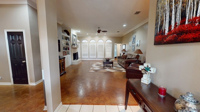 living area with ceiling fan, visible vents, crown molding, baseboards, and a fireplace with raised hearth