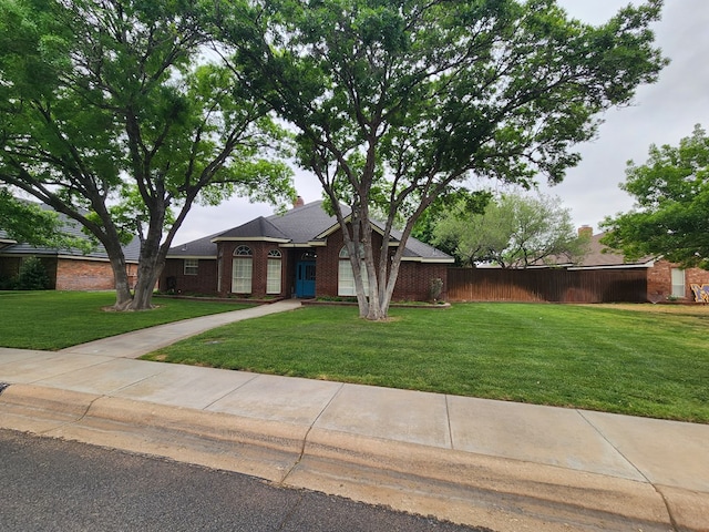 mid-century modern home with brick siding, fence, and a front yard