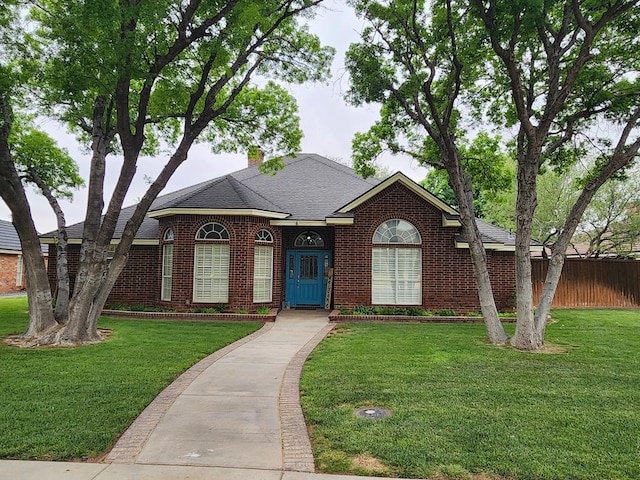 view of front of house featuring brick siding, a front yard, and roof with shingles