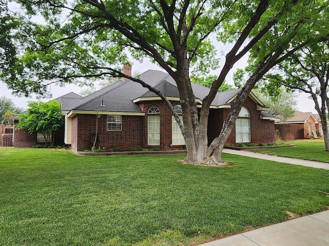 view of front of home featuring brick siding, a chimney, a shingled roof, and a front lawn