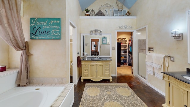 full bathroom featuring a high ceiling, tiled tub, two vanities, a spacious closet, and finished concrete floors