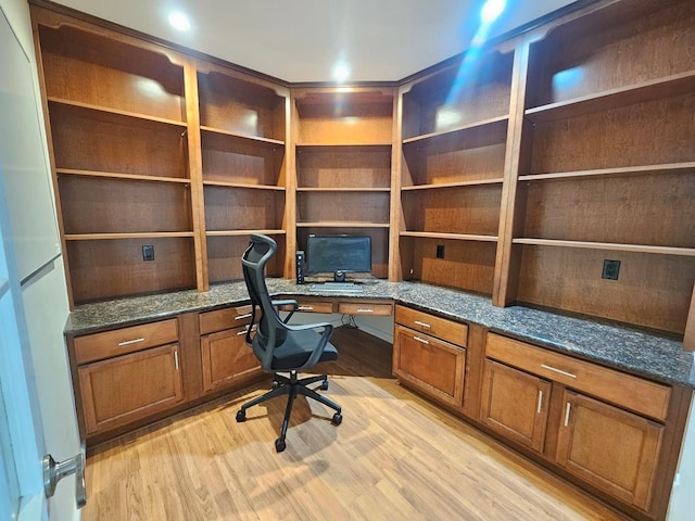 unfurnished office with built in desk and light hardwood / wood-style flooring