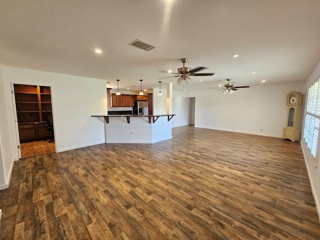 unfurnished living room featuring ceiling fan and dark wood-type flooring