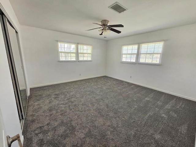 unfurnished bedroom featuring dark colored carpet, ceiling fan, and a closet