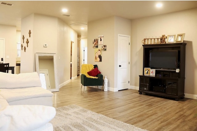 living area featuring light wood finished floors, visible vents, and baseboards