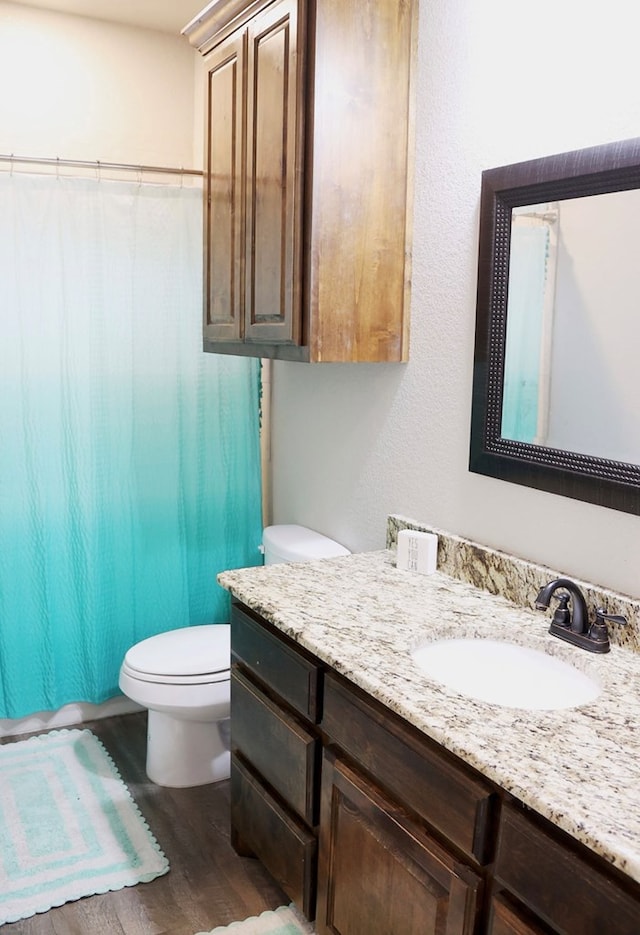 full bath with toilet, wood finished floors, and vanity