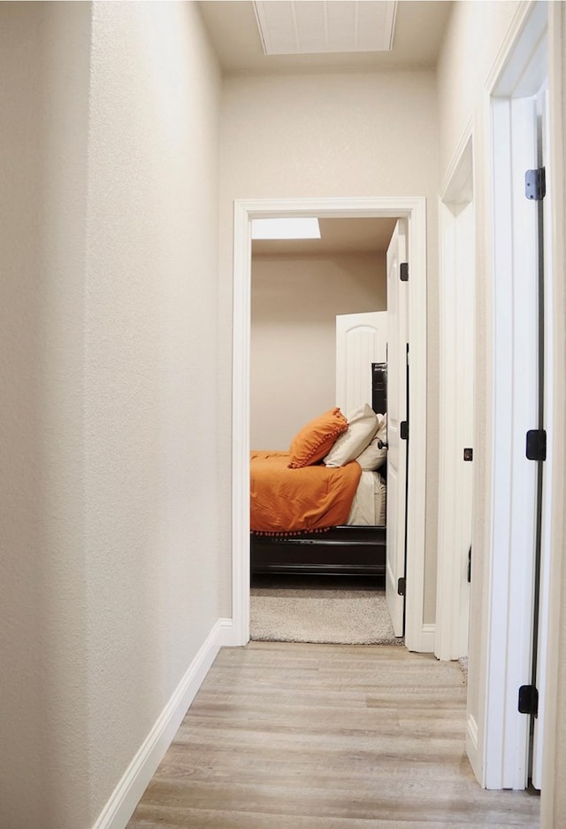 hallway featuring light wood-type flooring, visible vents, and baseboards