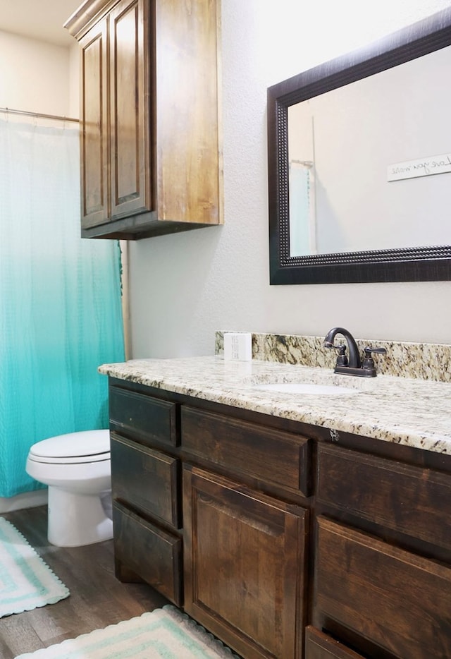 full bath with toilet, curtained shower, wood finished floors, and vanity