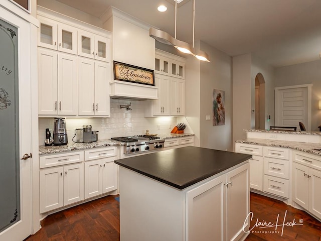 5300 Balfour Ct, Midland, TX 79707 - kitchen with arched walkways, stainless steel gas cooktop, white cabinetry, decorative backsplash, and glass insert cabinets