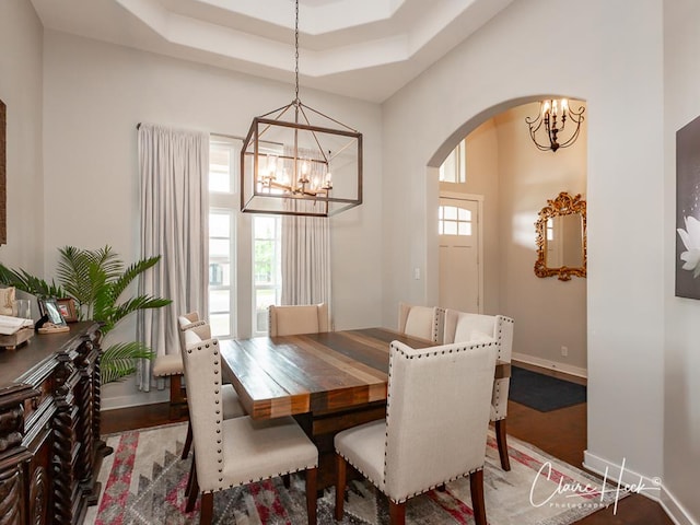 5300 Balfour Ct, Midland, TX 79707 - dining room featuring a chandelier, arched walkways, a raised ceiling, and wood finished floors