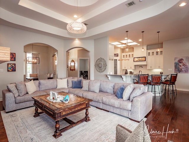 5300 Balfour Ct, Midland, TX 79707 - living room featuring dark wood finished floors, arched walkways, a chandelier, recessed lighting, and a tray ceiling