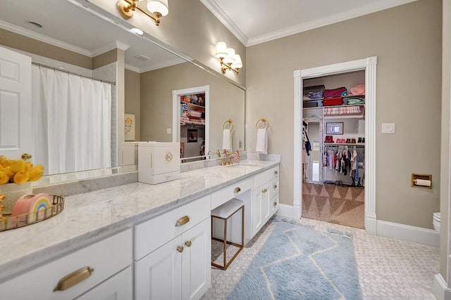 bathroom featuring baseboards, crown molding, a walk in closet, and vanity
