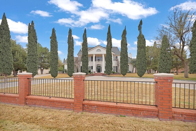 greek revival inspired property with a fenced front yard and a front lawn