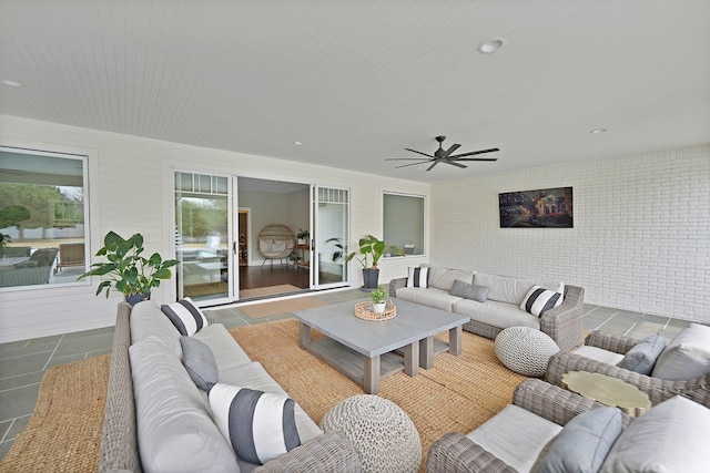 living area with ceiling fan and brick wall